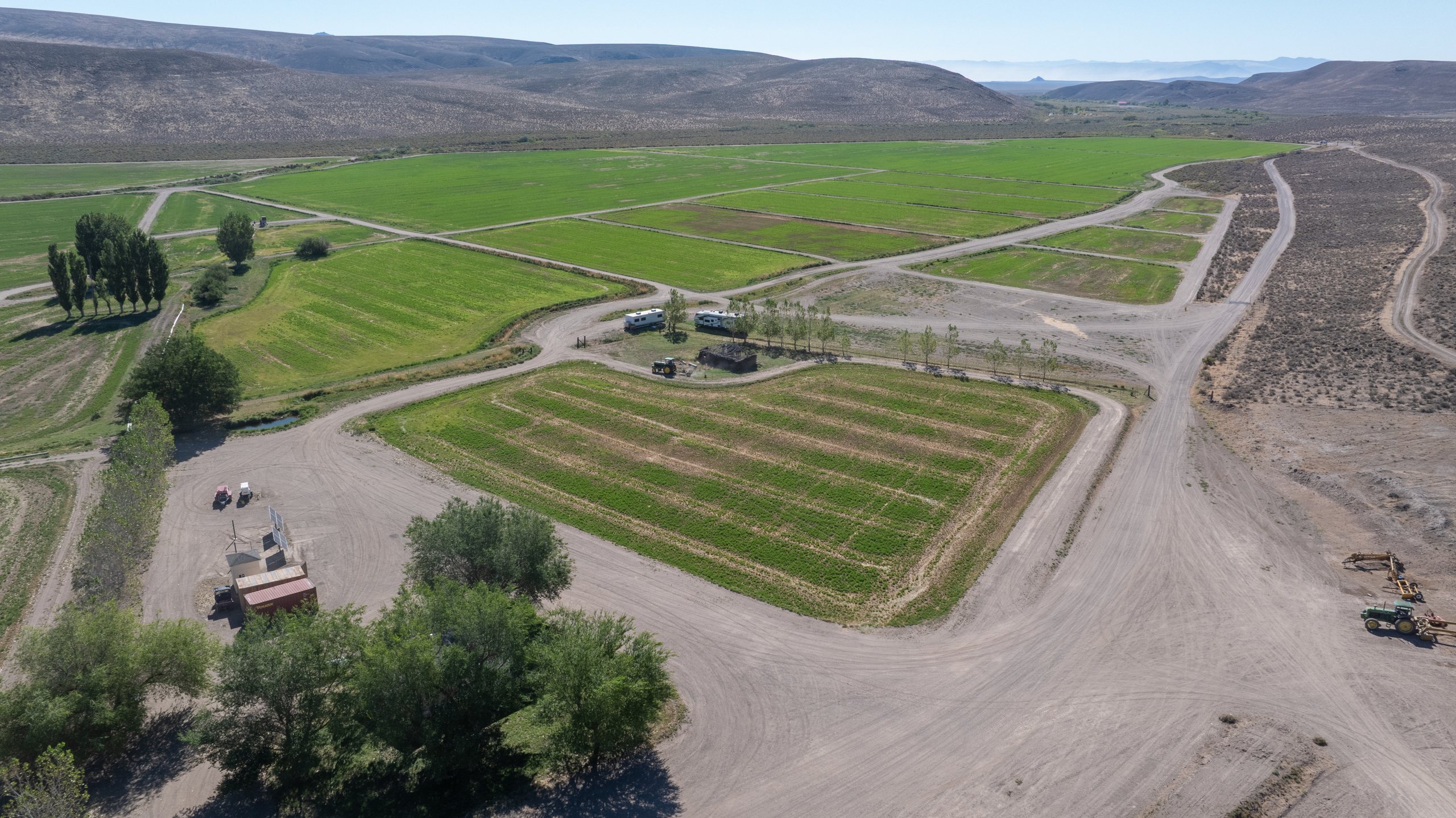 Aerial of a farm working yard with equipment and storage beside cultivated fields, northern Washoe County, Nevada